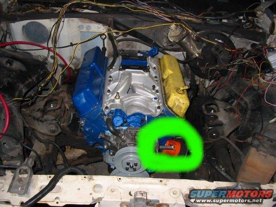 Engine bay with blue and yellow valve covers, a silver intake manifold, and a green circle around an orange distributor