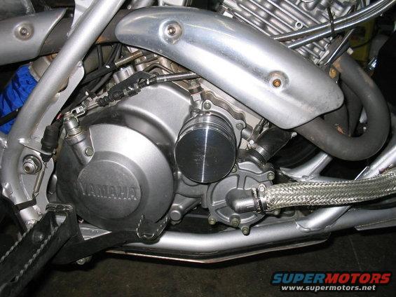 Close-up of a Yamaha motorcycle engine, showing the crankcase, water pump, and exhaust pipe
