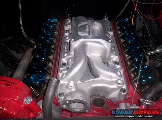 Aluminum intake manifold on a red engine block with blue roller rockers