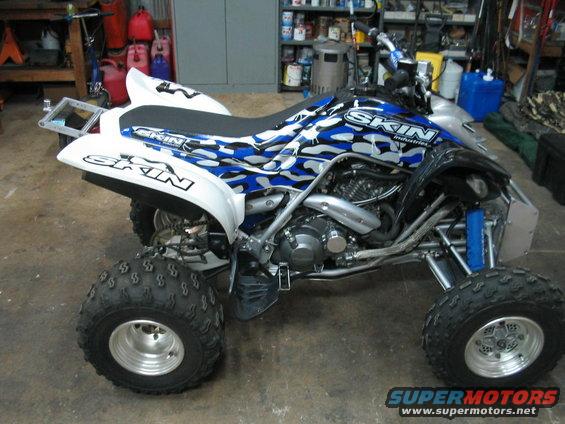 Quad bike with blue and white camouflage graphics. Text on the side says 'SKIN INDUSTRIES'