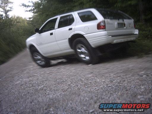 White 2000 Isuzu Rodeo SUV on a gravel road, right rear quarter view, tilted to the right
