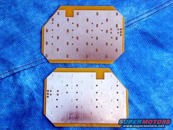 Two circuit boards with copper traces and solder points, laid on a blue textured surface