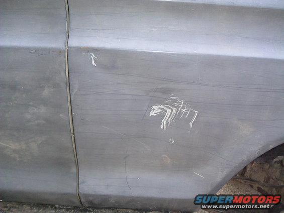 Close-up of a gray vehicle's side panel showing scratches and a white paint transfer mark