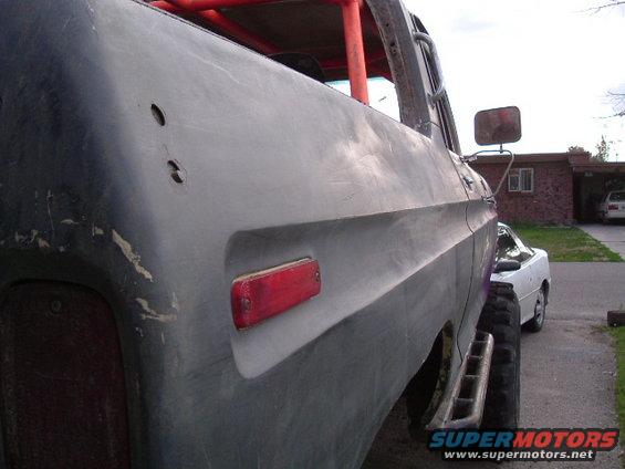 Side view of gray pickup truck with red roll cage and aftermarket bumper