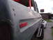 1979 Ford Bronco - A gray pickup truck with a red roll cage and aftermarket bumper is parked next to a white car.