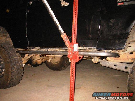 Black vehicle side view with rock sliders and hi-lift jack