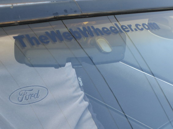 Ford logo on shirt reflected in rear window with TheWebWheeler.com sticker