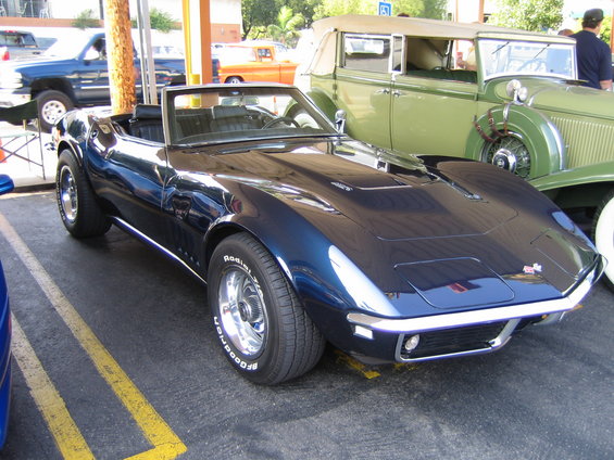 Dark blue convertible sports car parked next to a green vintage car