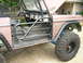 1995 Ford Bronco - This Ford Bronco features a custom roll cage and large off-road tires, with the driver's side door removed.