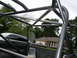 1995 Ford Bronco - Custom roll cage tubing is installed in the bed of a truck, with a residential house and trees behind.