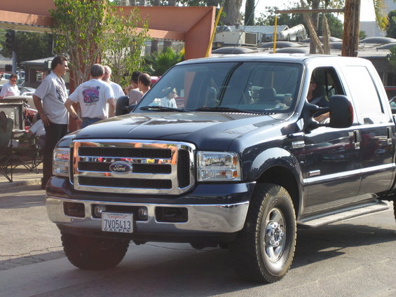 Dark blue Ford F-Series truck, front quarter view, chrome grille, visible license plate 7V05413