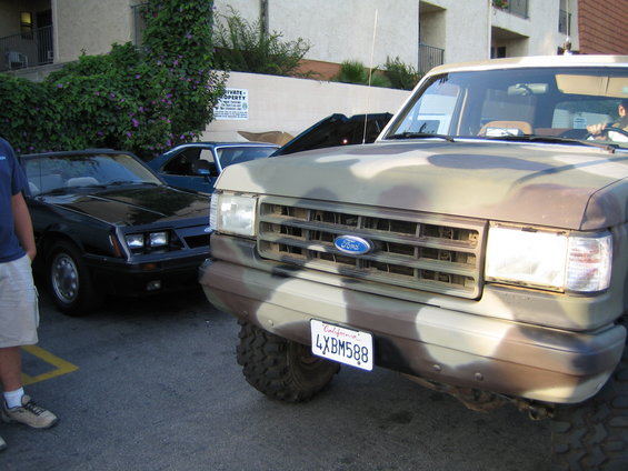Camouflaged Ford Bronco in front of a black convertible. License plate is 4XBM588