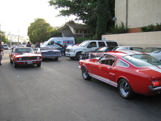 Red classic coupe with white stripes, parked on street with other cars