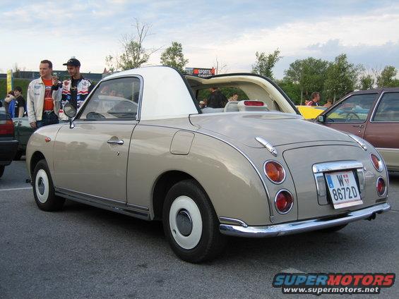 Tan convertible with white roof and white wheel covers, rear view
