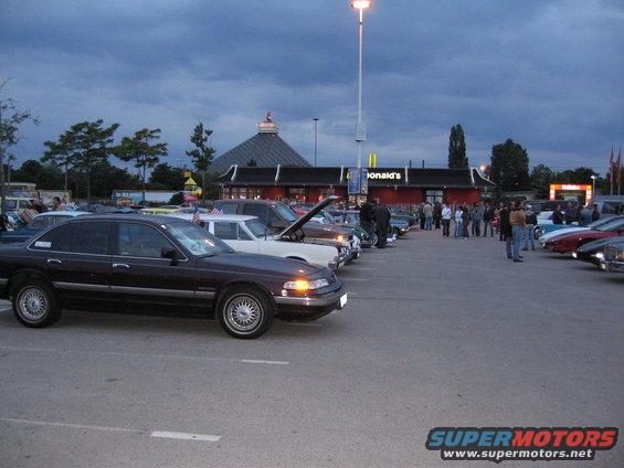 Dark sedan parked in a lot with other cars, McDonald's in background