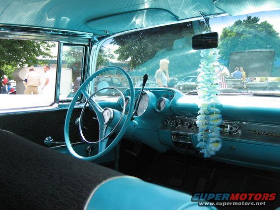Turquoise interior of a 1957 Chevrolet Bel Air, showing dashboard, steering wheel, and seats