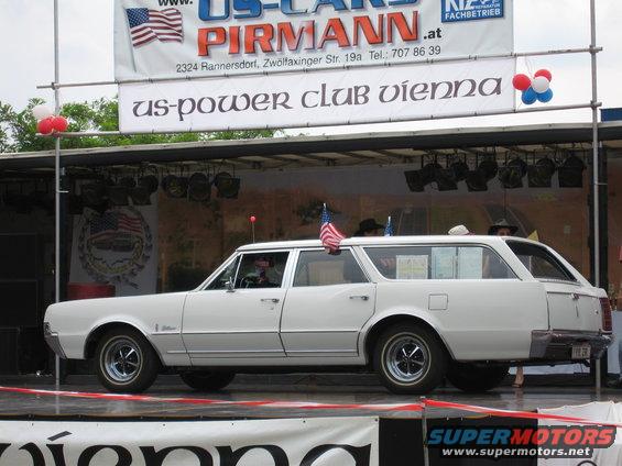 White station wagon on a stage with American flags