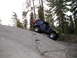 1989 Ford Bronco - Jeep Wrangler navigates a steep, rocky incline in a wooded area.