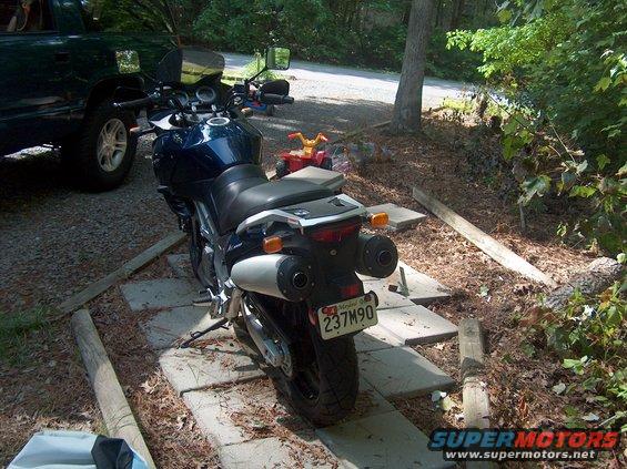 Dark blue motorcycle with dual exhaust pipes and a license plate reading 237M90