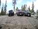 1989 Ford Bronco - Three off-road vehicles are parked on a rocky incline in a forest setting.