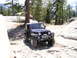 1989 Ford Bronco - A Jeep Wrangler TJ navigates a , mountainous terrain with pine trees and large boulders.