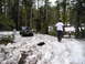 1989 Ford Bronco - A Jeep Wrangler navigates a snow-covered mountain path with two people observing.