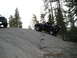 1989 Ford Bronco - Two off-road vehicles navigate a rocky incline in a wooded area.