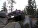 1989 Ford Bronco - A maroon Ford Bronco is shown off-roading over large rocks in a forest.