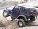 1989 Ford Bronco - Jeep Wrangler TJ navigating rocky terrain with a person lying beneath it.
