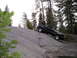 1989 Ford Bronco - Pickup truck navigating a steep rock incline in a wooded mountain area.