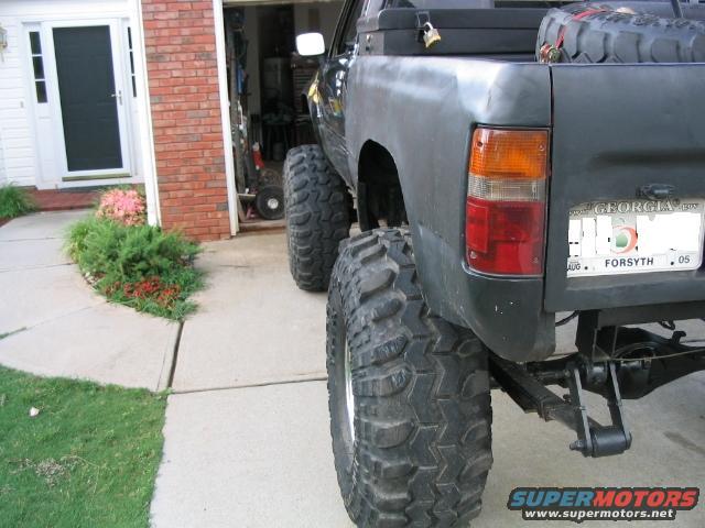Black Toyota pickup truck with large off-road tires, spare tire in bed, and Georgia license plate