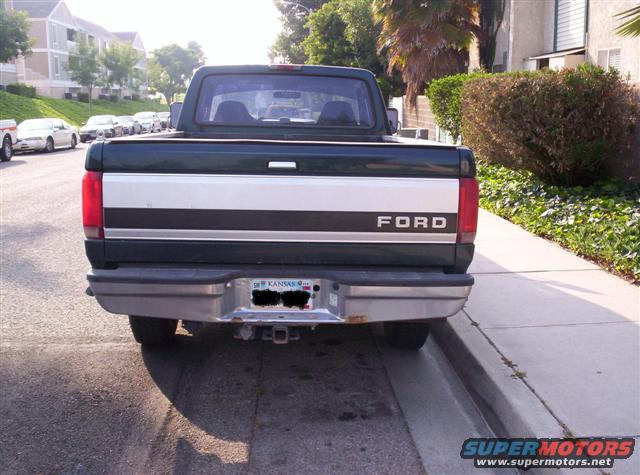 Dark green Ford pickup truck, rear view, with a silver stripe and 'FORD' lettering