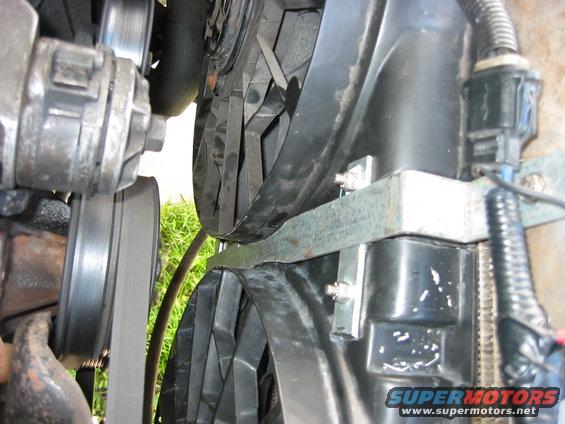 img_0755.jpg A simple 1 inch wide piece of aluminum I bent to follow the countours of the fan shrouds. This is stuck into the bottom of the core support where a lip comes up so it cant move back toward the engine. Tension is from the bolt on the top that attaches it to the radiator lip. One bolt and the fan assembly comes out. Not sure how I like this yet, I think it needs more support.
