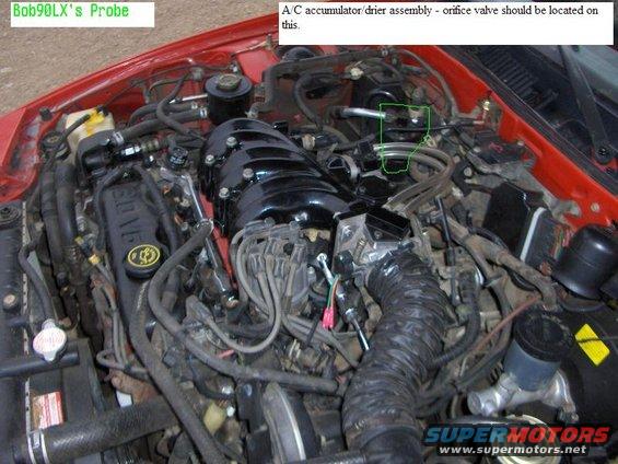 Engine bay with V6 engine cover and various hoses and components. Text indicates A/C accumulator/drier assembly