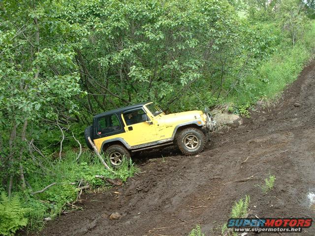Yellow Jeep Wrangler on a muddy incline, 1997-2006 model