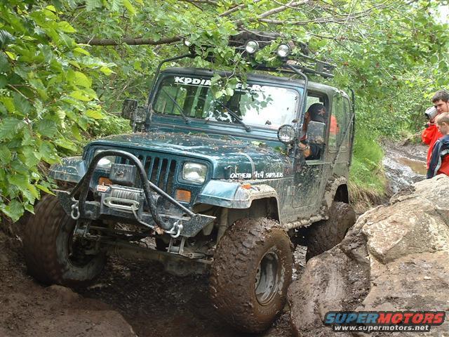 Green Jeep Wrangler with winch, off-roading through mud and rocks