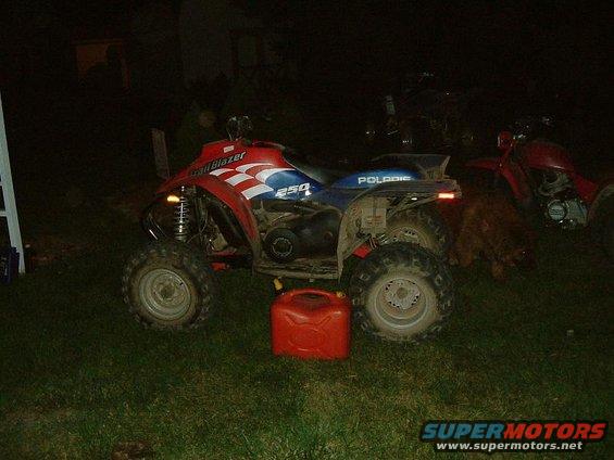 Red and blue Polaris ATV with a red gas can. Another ATV is visible in the background