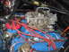 1972 Ford Mustang - Engine bay detail a carburetor and distributor with red spark plug wires.