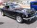 1972 Ford Mustang - A black 1965 Ford Mustang fastback is parked with its hood open, revealing the engine bay.