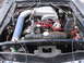 1972 Ford Mustang - The engine bay of a 1972 Ford Mustang, a V8 engine with a prominent intake system and red spark plug wires.