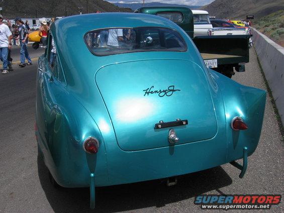 Teal custom coupe with 'Henry J' script on trunk lid, parked behind other vehicles
