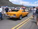 1972 Ford Mustang - A classic orange muscle car is seen from the rear on a sunny day at an outdoor event.