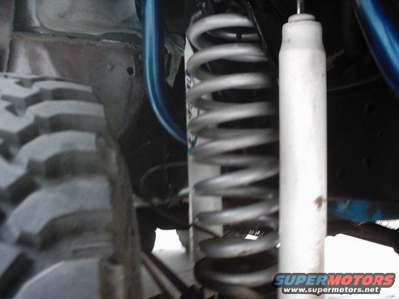Close-up of a vehicle's suspension with a large coil spring and white shock absorber