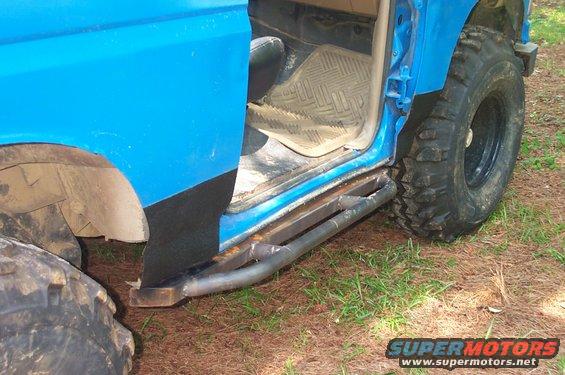 Blue SUV side view with custom metal steps and large tires