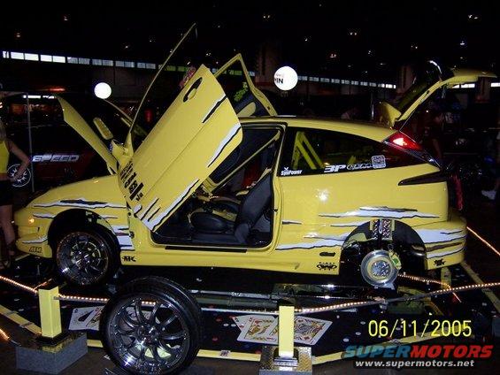 Yellow 2005 Ford Focus with lambo doors open, custom graphics, and aftermarket wheels