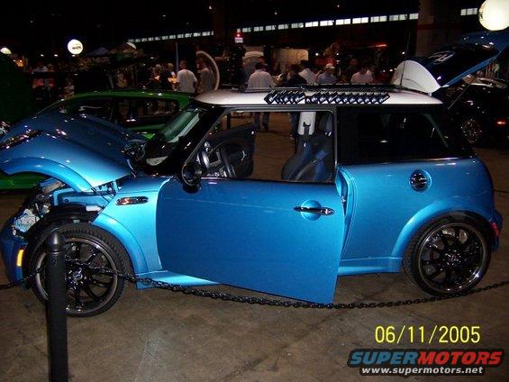 Blue Mini Cooper with hood and driver's door open, parked next to a green car. Date stamp reads 06/11/2005