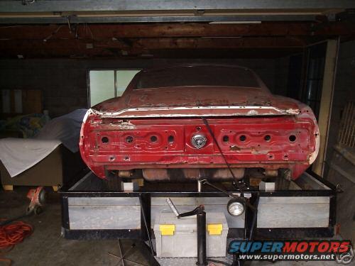 Red 1969 Ford Mustang rear end on a trailer, missing taillights and bumper