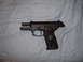 1988 Ford Bronco - A black semi-automatic pistol is shown against a light blue, wrinkled fabric background.