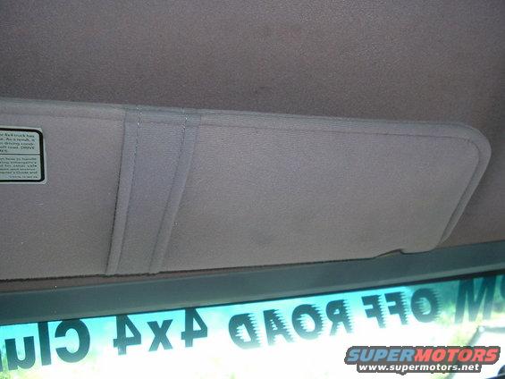 Sun visor in a vehicle, with a sticker on the left and a reflection of '4x4 Club Off Road' text on the windshield