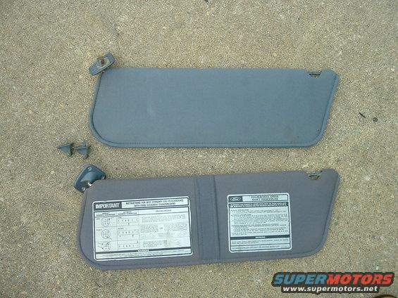 Two gray car sun visors with attached mounting hardware and informational stickers